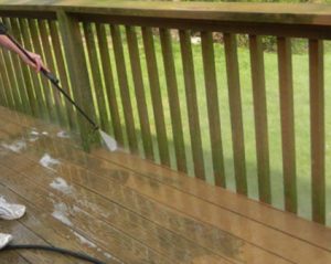 man powerwashing a wooden deck